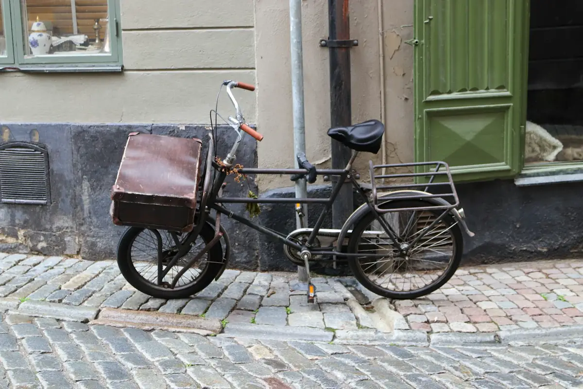 A cargo bicycle with a large front box sits on a cobblestone street.